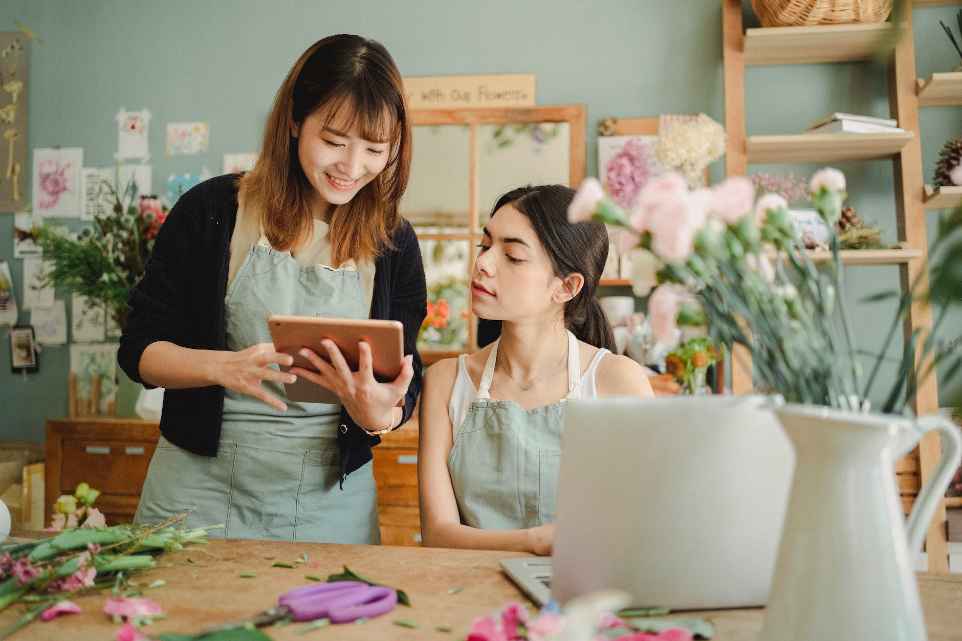 positive multiracial women with gadgets in floral shop